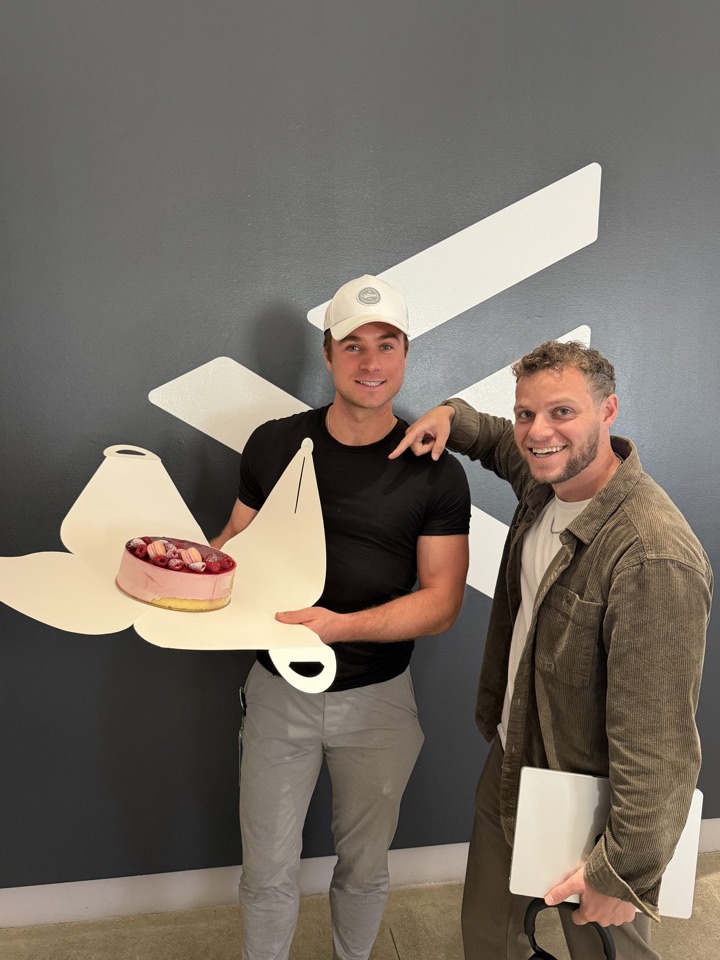 Two people at the F.inc office holding up a delivered pitch cake