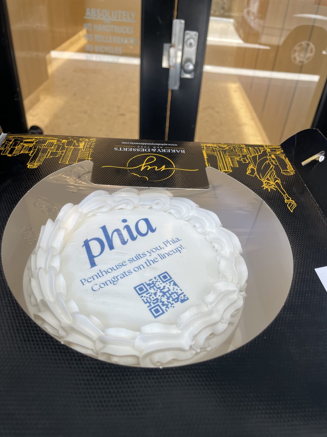 A white cake printed with the Phia logo and a QR code